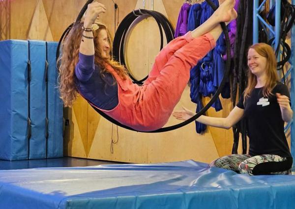 An inclusive aerial rings session, with participant suspended in the hoop mid shot.