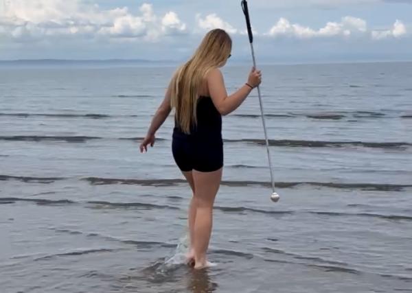Young person paddling in shallow water on the beach