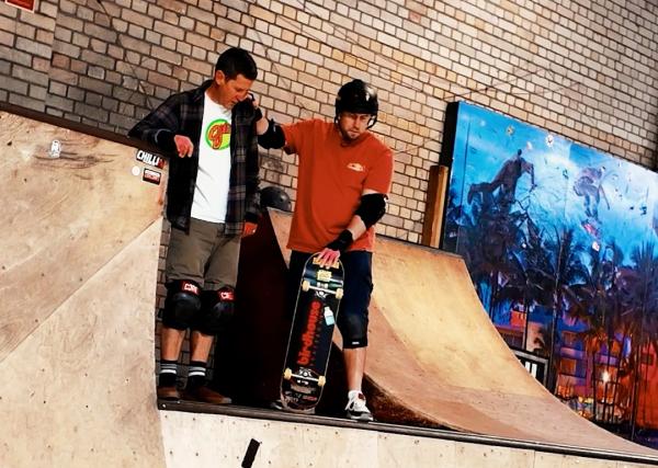 Visually impaired skateboarder on the coping of a bowl, ready to drop in