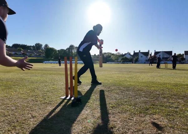 silhouetted adaptive cricket player, mid bat swing 